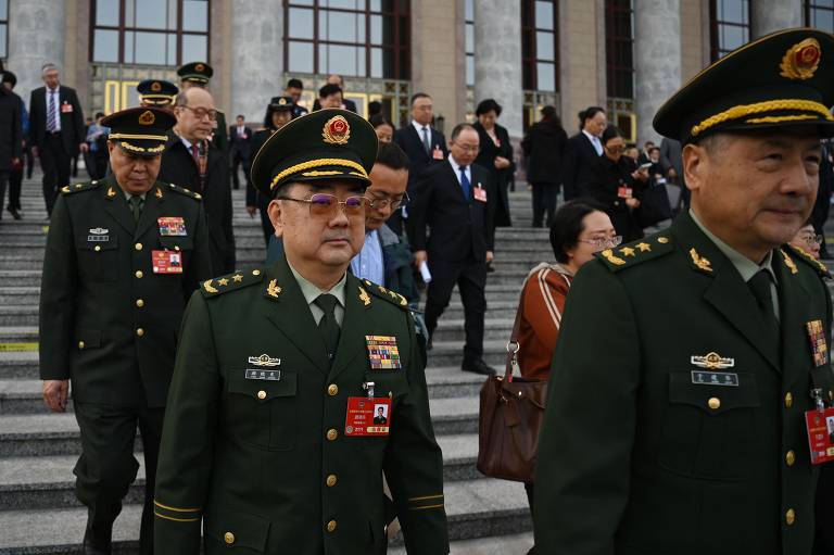 A imagem mostra um grupo de homens e mulheres, alguns em uniformes militares, descendo as escadas de um edifício. Os homens em destaque usam uniformes verdes com insígnias e chapéus, enquanto outras pessoas ao fundo estão vestidas de maneira formal. O ambiente parece ser um local oficial, possivelmente um edifício governamental.