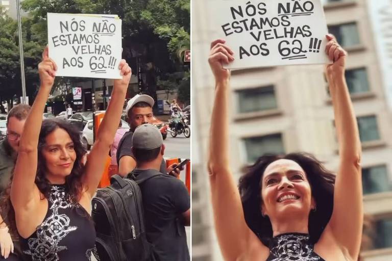 Uma mulher está em pé em uma rua movimentada, segurando um cartaz acima da cabeça. O cartaz diz: 'NÓS NÃO ESTAMOS VELHAS AOS 60!!!'. A mulher está sorrindo e vestindo um vestido preto com detalhes em branco. Ao fundo, há várias pessoas e edifícios.