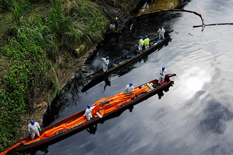 Pessoas trabalham na retirada de óleo do rio Viche após vazamento de oleoduto que atingiu cursos d'água na província de Esmeraldas