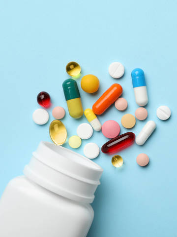 Bottle and scattered pills on color background, top view. Space for text - (Photo: New Africa/Adobe Stock) DIREITOS RESERVADOS. NÃO PUBLICAR SEM AUTORIZAÇÃO DO DETENTOR DOS DIREITOS AUTORAIS E DE IMAGEM