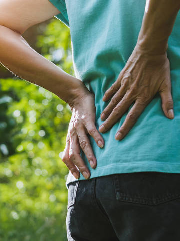 Closeup hands of woman touching her back pain in healthy concept on nature background. (Foto:Mintra/Adobe Stock )