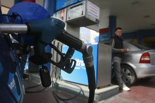 An employee prepares to fill up a customer's car in a gas station after concerns of petrol shortages led to panic buying in Athens