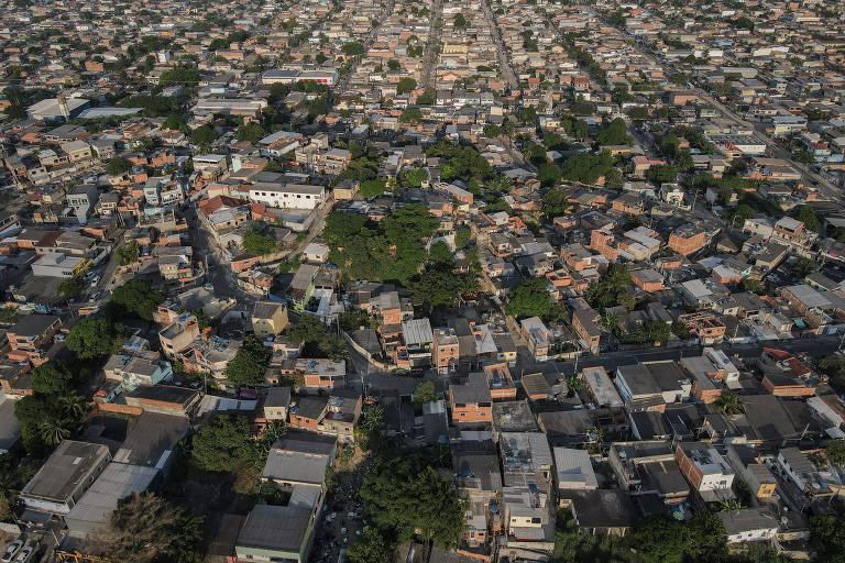 Imagem aérea de uma área urbana densamente povoada， com uma grande quantidade de casas e edifícios dispostos de forma irregular. A vegetação é visível entre as construções， com árvores espalhadas pela região. As ruas são estreitas e sinuosas， conectando as diferentes áreas residenciais.