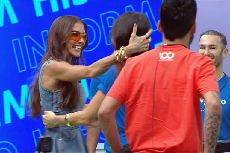 A imagem mostra um grupo de pessoas interagindo em um ambiente descontraído. Uma mulher com cabelo longo e solto, vestindo um vestido jeans, está sorrindo e abraçando outra mulher. Ao fundo, há um homem com uma camiseta azul e outro com uma camiseta vermelha, ambos sorrindo. O fundo da imagem é azul com texto em destaque que diz 'INFORM'.