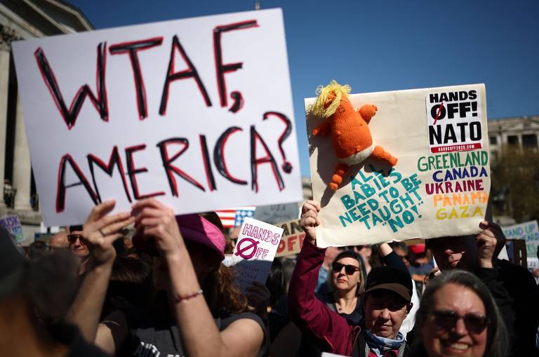 As pessoas seguravam cartazes com dizeres como 'Orgulhoso Americano Envergonhado'; a multidão cantava 'Tire suas mãos do Canadá', 'Tire suas mãos da Groenlândia' e 'Tire suas mãos da Ucrânia' enquanto ouvia discursos contra Trump