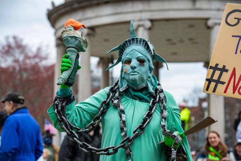 Manifestante vestido como uma Estátua da Liberdade acorrentada participa do ato em Boston