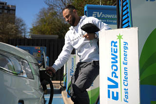 A man charges an electric vehicle at an EV power charging station in Archway in London