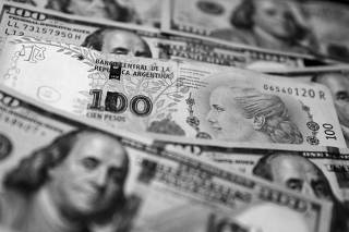 FILE PHOTO: A one hundred Argentine peso bill sits on top of several one hundred U.S. dollar bills in this illustration picture