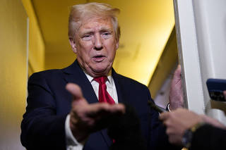 U.S. President Donald Trump speaks to members of the media onboard Air Force One, on a flight to Joint Base Andrews