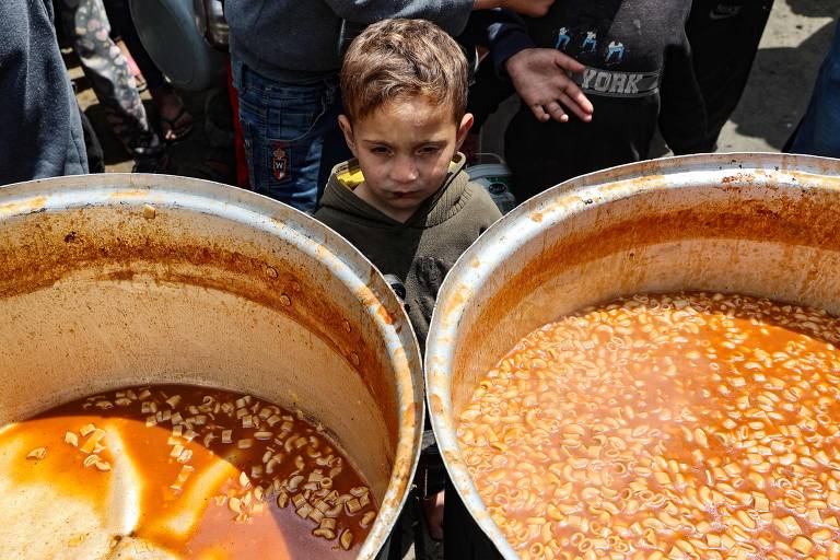 Criança diante de panela para refeição comum em Gaza; em 2 de março, Israel impôs um bloqueio de ajuda humanitária ao território palestino