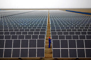 FILE PHOTO: A worker inspects solar panels at a solar farm in Dunhuang