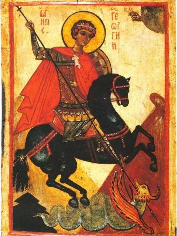 A imagem retrata um ícone religioso de São Jorge montado em um cavalo negro. Ele está vestido com uma armadura e uma capa vermelha, segurando uma lança. O fundo é decorado com elementos que sugerem um ambiente celestial, incluindo nuvens e uma figura no canto superior direito. Abaixo do cavalo, há uma representação de um dragão ou serpente, simbolizando a luta de São Jorge contra o mal.