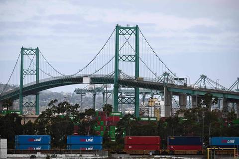 Vehicles cross the Vincent Thomas bridge as shipping containers sit stacked on a train at the Port of Los Angeles in San Pedro, California on April 15, 2025. US President Donald Trump ordered a probe April 15, 2025 that may result in tariffs on critical minerals, rare-earth metals and associated products such as smartphones, in an escalation of his dispute with global trade partners. China said April 16, 2025 its economy topped forecasts in the first quarter, as exporters rushed to shift goods ahead of swingeing US tariffs, but warned it faced 