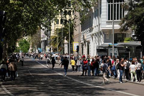 People walk in downtown Madrid or wait for the bus (R) during a massive power cut affecting the entire Iberian peninsula and the south of France, in Madrid on April 28, 2025. A 