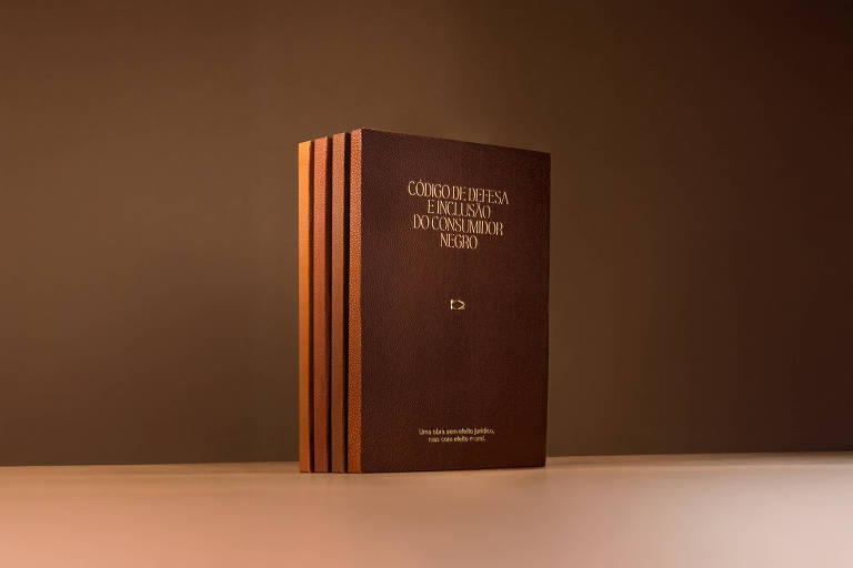 A imagem mostra um dicionário de capa dura, com uma coloração marrom e detalhes em dourado. O dicionário está posicionado verticalmente sobre uma superfície clara, com um fundo neutro e escuro. O título visível na capa é "CÓDIGO DE DEFESA DO CONSUMIDOR" e "DICIONÁRIO MÁRIO NERIO".