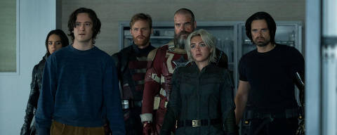 Cena do filme Thunderbolts com Wyatt Russell, David Harbour, Sebastian Stan, Hannah John-Kamen, Lewis Pullman e Florence Pugh *** Local Caption *** A imagem mostra um grupo de seis personagens em um ambiente interno. Eles estão em pé, com expressões sérias e focadas. O primeiro personagem à frente é um jovem com cabelo castanho e roupas casuais. Atrás dele, há uma mulher com cabelo longo e escuro, vestindo um traje preto. O terceiro personagem é um homem com cabelo loiro e barba, usando uma armadura vermelha. O quarto é um homem com cabelo grisalho e barba, também em traje de combate. A quinta personagem é uma mulher com cabelo curto e platinado, vestindo um traje escuro. O último personagem à direita é um homem com cabelo escuro e um braço mecânico, vestido de preto. O fundo é de um ambiente moderno, com paredes claras e arm
