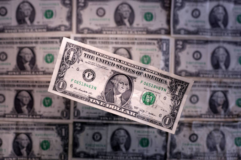 A imagem mostra uma nota de um dólar dos Estados Unidos em primeiro plano, com o retrato de George Washington. Ao fundo, há várias notas de um dólar dispostas em uma superfície, criando um efeito de repetição. A nota em destaque possui detalhes em verde e preto, com a inscrição 'The United States of America' e o valor 'One Dollar'.
