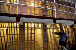 FILE PHOTO: A visitor to Alcatraz Island's former federal prison leans against a B Block cell in the San Francisco Bay