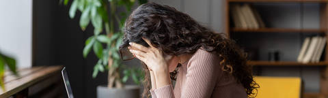 Exhausted upset woman sit at desk hide face in hands tired of difficult tasks. Stressed frustrated female employee feel headache work overtime suffer from burnout at workplace. Stressed businesswoman.Credit DimaBerlin / AdobeStock