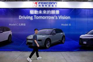 A person walks past an advertisement for Foxconn at E-Mobility exhibition in Taipei