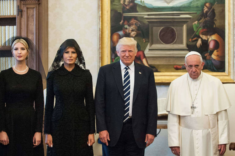 A imagem mostra quatro pessoas em um ambiente interno, possivelmente uma sala do Vaticano. À esquerda, duas mulheres vestindo roupas pretas e véus, seguidas por um homem de terno e gravata, e à direita, um homem idoso vestido de branco, que parece ser um líder religioso. Ao fundo, há uma pintura clássica na parede.