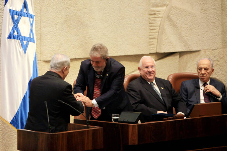 O presidente israelense Benjamin Netanyahu (esq) aperta a mão de Lula durante uma sessão parlamentar em Jerusalém; participaram o ex-presidente de Israel Shimon Peres (dir) e o presidente do Parlamento, Reuven Rivlin (c); é a primeira visita de um chefe de Estado brasileiro à região