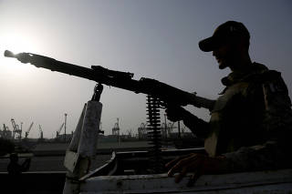 A paramilitary trooper mans a gun atop a vehicle as he keeps guard during a media tour of the Karachi Port