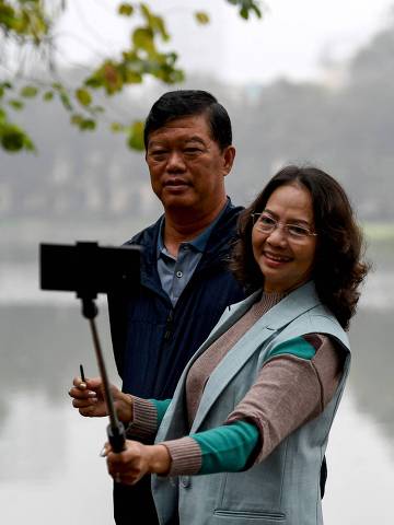 A couple take a selfie photo by Hoan Kiem Lake in Hanoi on February 9, 2023. (Photo by Nhac NGUYEN / AFP)