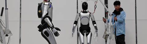 A humanoid robot walks as employees conduct tests on the robots, on the production line at the AgiBot factory in Shanghai, China March 20, 2025. REUTERS/Florence Lo ORG XMIT: HFSPEK01