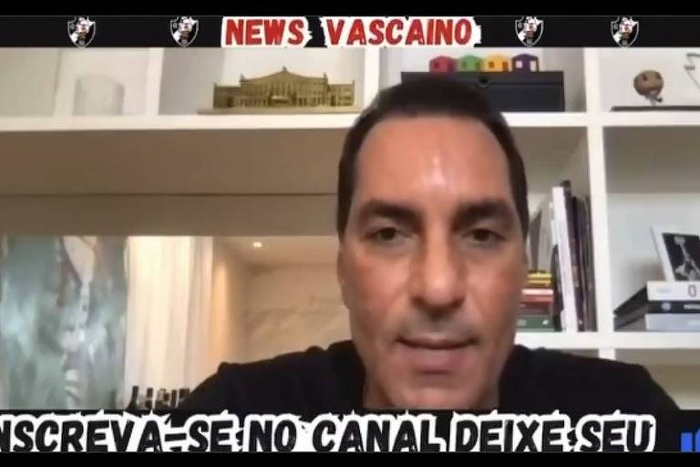 Um homem está falando em um vídeo, com um fundo que mostra prateleiras com livros e objetos decorativos. Na parte superior da imagem, está escrito 'NEWS VASCAINO'. Na parte inferior, há um texto que diz 'INSCREVA-SE NO CANAL DEIXE SEU'.