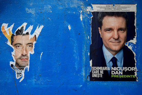 A torn out poster featuring presidential candidate George Simion is seen next to one of Nicusor Dan, with the writing 