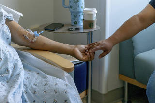 Oscar Larrainzar, recipient of the first-ever human bladder transplant, reaches his wife?s hand while waiting to be discharged from the Ronald Reagan UCLA Medical Center in Los Angeles, May 13, 2025. (Kyle Grillot/The New York Times)
