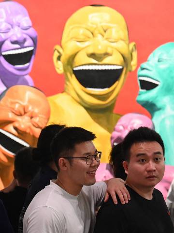 TOPSHOT - Visitors look at works by Chinese artist Yue Minjun on display at the Art Basel international art fair in Hong Kong on March 28, 2025. (Photo by Peter PARKS / AFP) / RESTRICTED TO EDITORIAL USE - MANDATORY MENTION OF THE ARTIST UPON PUBLICATION - TO ILLUSTRATE THE EVENT AS SPECIFIED IN THE CAPTION
