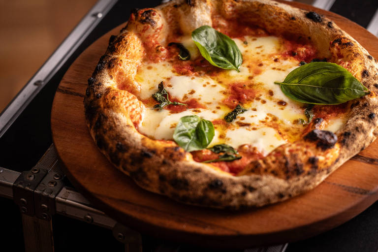 Uma pizza Margherita recém-assada, com bordas crocantes e queimadas levemente. A pizza está coberta com molho de tomate, queijo derretido e folhas de manjericão fresco. Ela está disposta em uma tábua de madeira, com um fundo que sugere um ambiente rústico.
