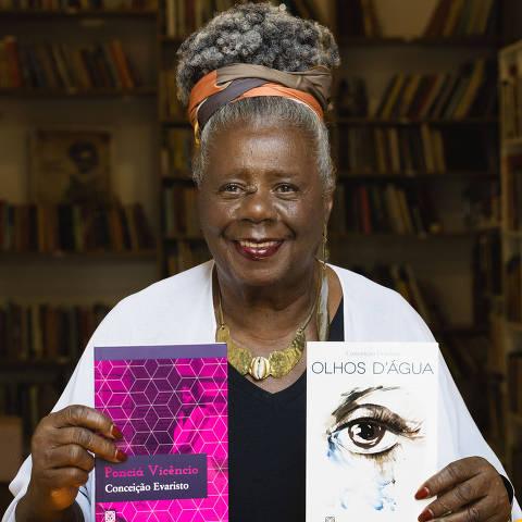 A escritora Conceição Evaristo com dois de seus livros publicados pela Pallas Editora