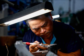 A worker makes plastic injection molding for various car parts at Long Team Industrial in Tainan