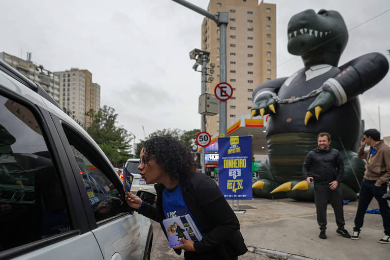 A imagem mostra uma mulher com cabelo cacheado e óculos, interagindo com um carro, enquanto segura um folheto. Ao fundo, há um grande dinossauro inflável vestido com um terno, que parece ser parte de uma promoção. O ambiente é urbano, com prédios e sinais de trânsito visíveis. Algumas pessoas estão caminhando na cena, e o clima parece nublado.