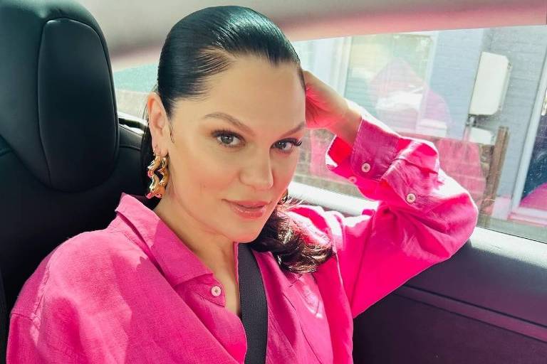 Em foto colorida,mulher de vestido rosa posa para foto
