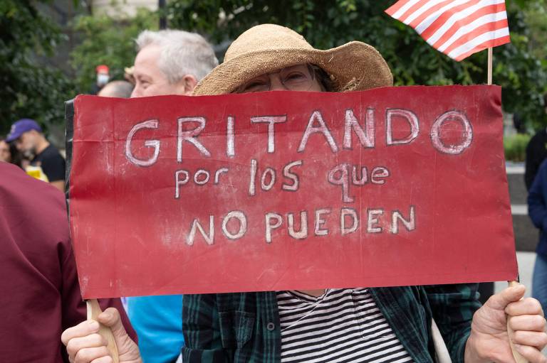 Mulher segura um cartaz que diz: 'gritando por aqueles que não podem'; manifestantes vãos às ruas de Los Angeles pelo quarto dia contra a política de imigração do presidente Donald Trump