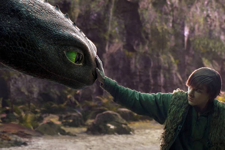 Uma cena de um filme de animação onde um menino está acariciando a cabeça de um dragão. O dragão é grande, com escamas escuras e olhos verdes. O ambiente ao redor é natural, com vegetação densa e uma atmosfera mágica. O menino está vestido com roupas simples e parece estar em um momento de conexão com o dragão.
