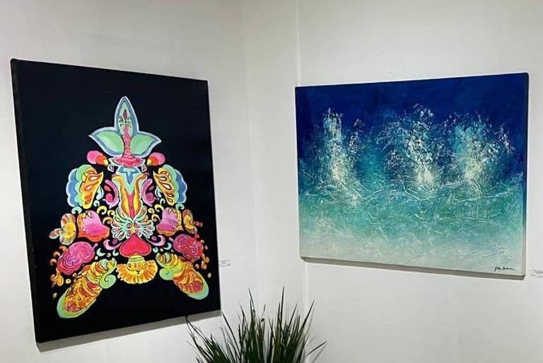 A imagem mostra uma galeria de arte com quatro obras expostas. À esquerda, há uma pintura colorida com formas e elementos florais em um fundo escuro. No centro, uma obra em tons de azul que representa um efeito aquático. À direita, duas pinturas em tons de laranja e dourado, com texturas que lembram folhas ou elementos naturais. No chão, há uma planta em vaso, e o piso é de cerâmica clara.