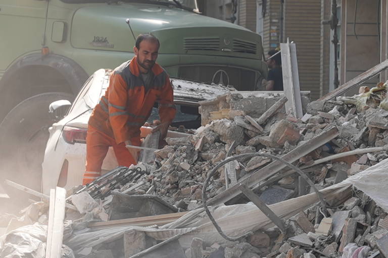 Um socorrista tenta remover escombros de edifícios danificados durante ataques israelenses em Teerã, Irã