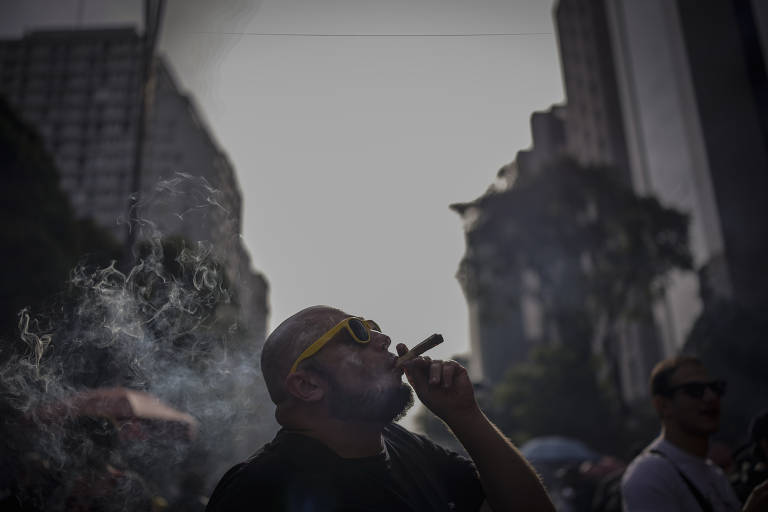 O analista de sistemas Tiago Souza, 44, fuma cigarro feito a mão durante Marcha da Maconha, na avenida Paulista, em São Paulo; manifestantes pediram a legalização do cultivo da cannabis
