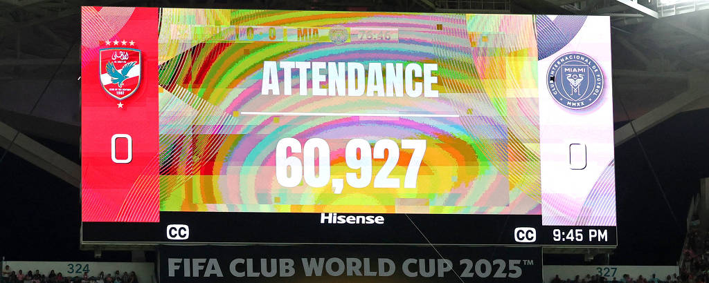 A imagem mostra um estádio lotado durante um jogo da Copa do Mundo de Clubes da FIFA 2025. No placar eletrônico, está indicado que a assistência é de 60.927 pessoas. O ambiente é vibrante, com torcedores visivelmente animados nas arquibancadas. O placar também exibe o resultado do jogo, 0 a 0.