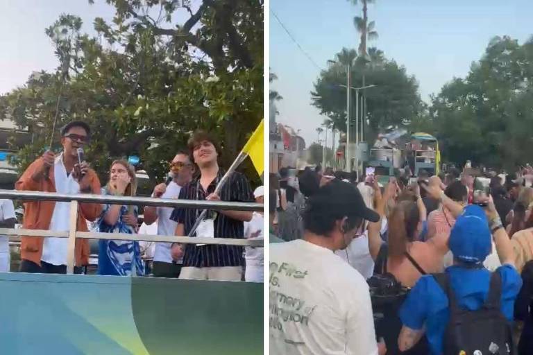 A imagem mostra um evento ao ar livre. À esquerda, um grupo de pessoas está em um carro de som, com uma pessoa segurando um microfone e outras acenando. À direita, uma multidão de pessoas está reunida, algumas segurando bandeiras e outras com roupas coloridas, em um ambiente festivo. Árvores e palmeiras são visíveis ao fundo, sugerindo um clima tropical.