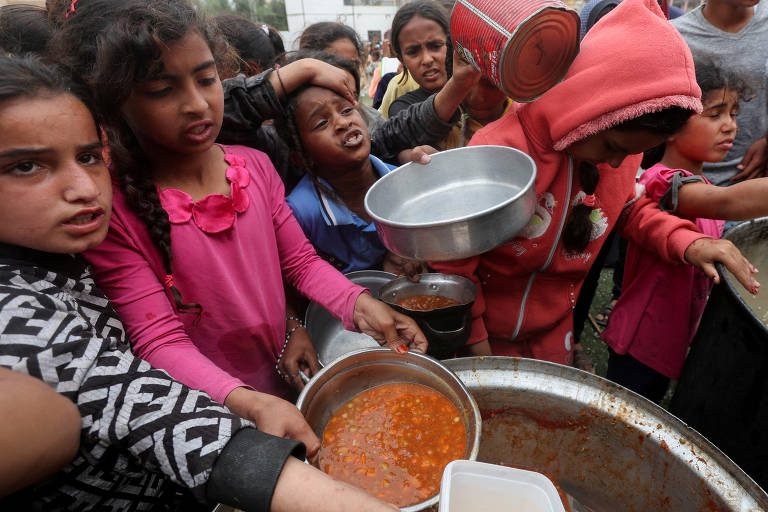 Palestinos se reúnem para receber alimentos de cozinha beneficente em Nuseirat, no centro da Faixa de Gaza