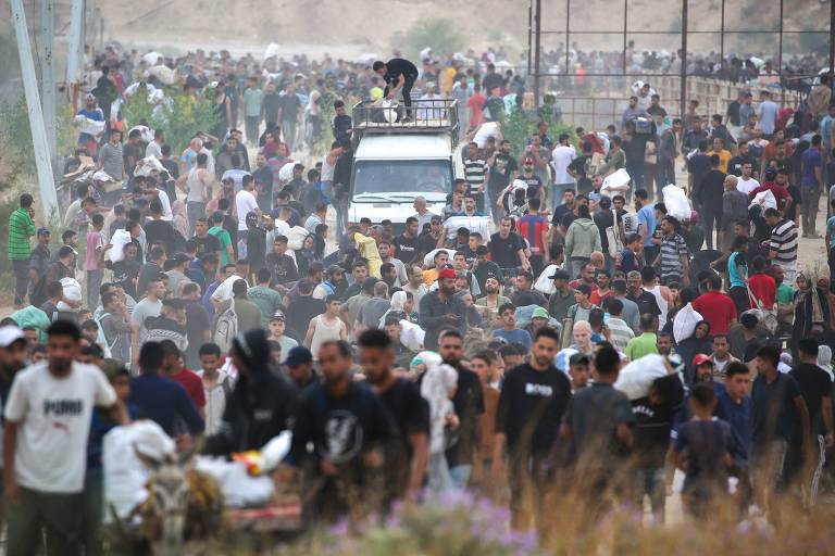 Palestinos deslocados carregam suprimentos de alívio após retornar de centro de distribuição