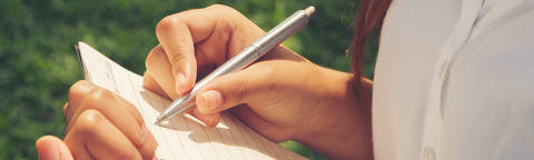 Close up hand of young woman writing book at the park. - (Photo: Lealnard/Adobe Stock)