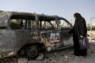 A woman looks at an ambulance burned by Israeli attacks on a street in Tehran