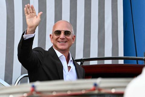 Amazon's founder Jeff Bezos waves as he gets on a taxi boat at the Aman Hotel in Venice on June 26, 2026. Celebrities in superyachts sail into Venice this week for the three-day wedding party of Amazon tycoon Jeff Bezos and Lauren Sanchez, despite irate locals who say the UNESCO city is no billionaire's playground. The tech magnate and journalist have reportedly invited about 200 guests to their multi-million dollar nuptials in the Italian city, which are expected to kick off on June 26 and end Saturday with a ceremony at a secret location. (Photo by Stefano Rellandini / AFP)